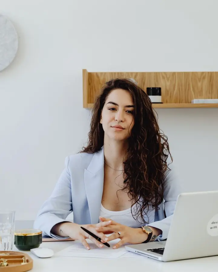 A clinic owner smiling at her desk with her laptop open.