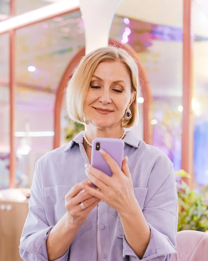 A client smiling as she books on her phone.